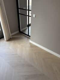 Hongaarse punt Julia greige eiken PVC vloer van Stile Floors – warme houtlook voor huiselijke ruimtes.
